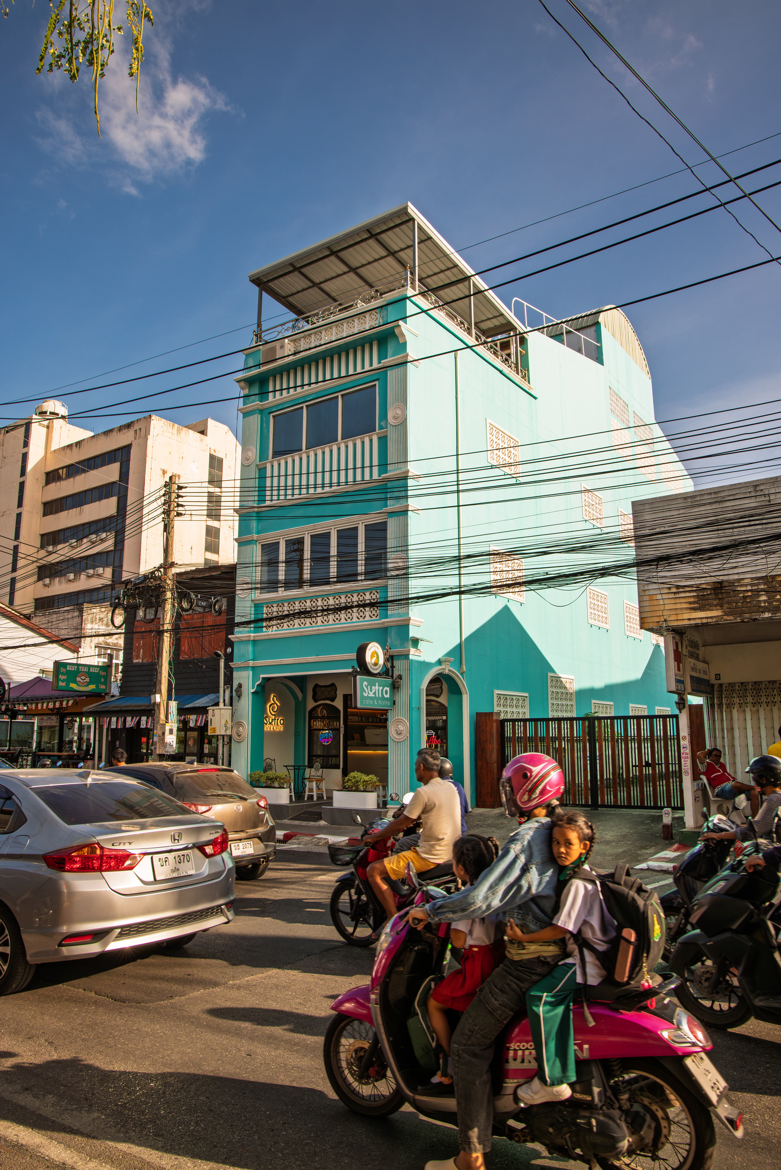 Turquoise Sutra cafe building facade with motorbikes parked outside, Phuket Old Town — architectural photography by Samuel John Ford