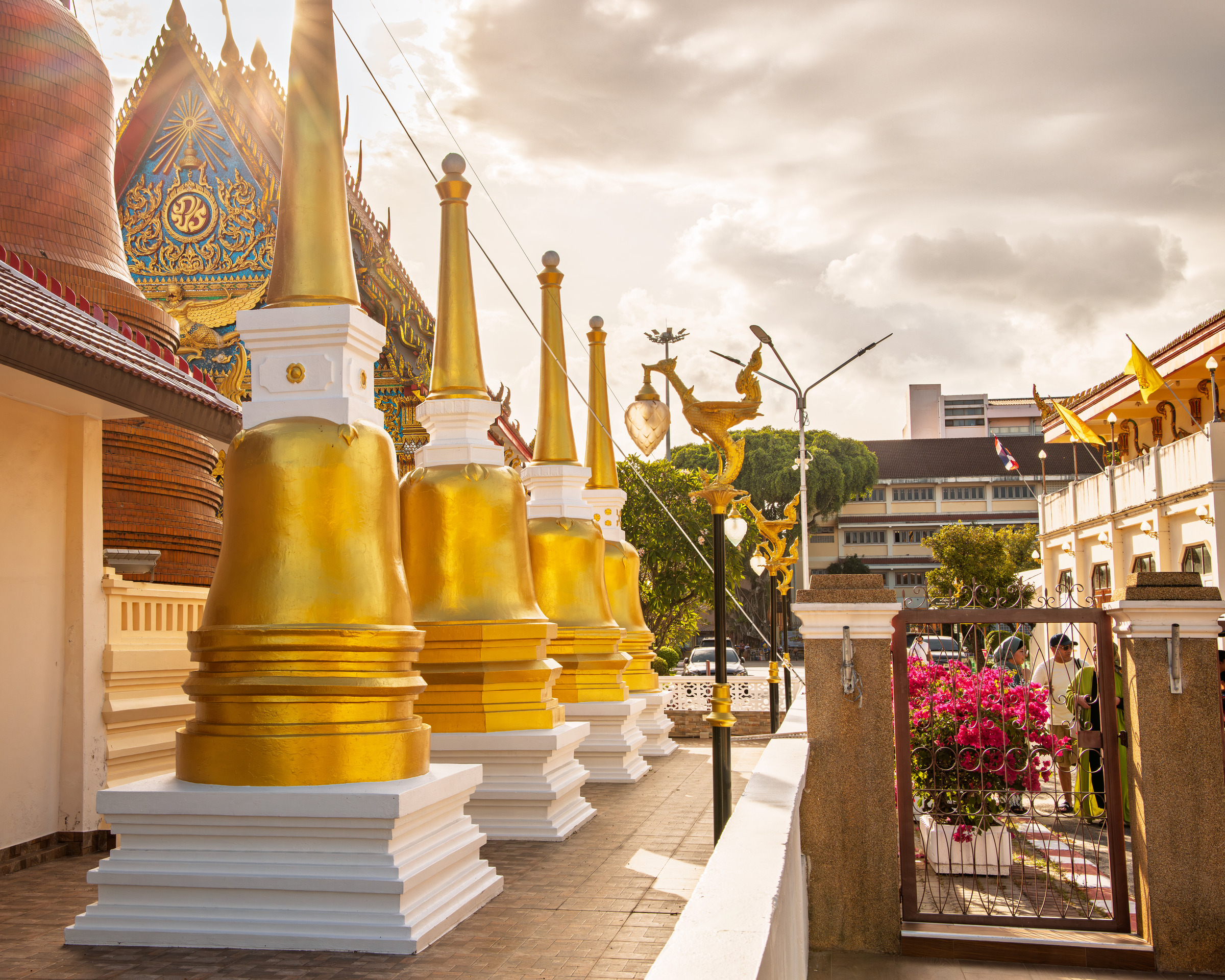 Golden temple stupas gleaming against blue sky, Buddhist architecture in Thailand — architectural photography by Samuel John Ford