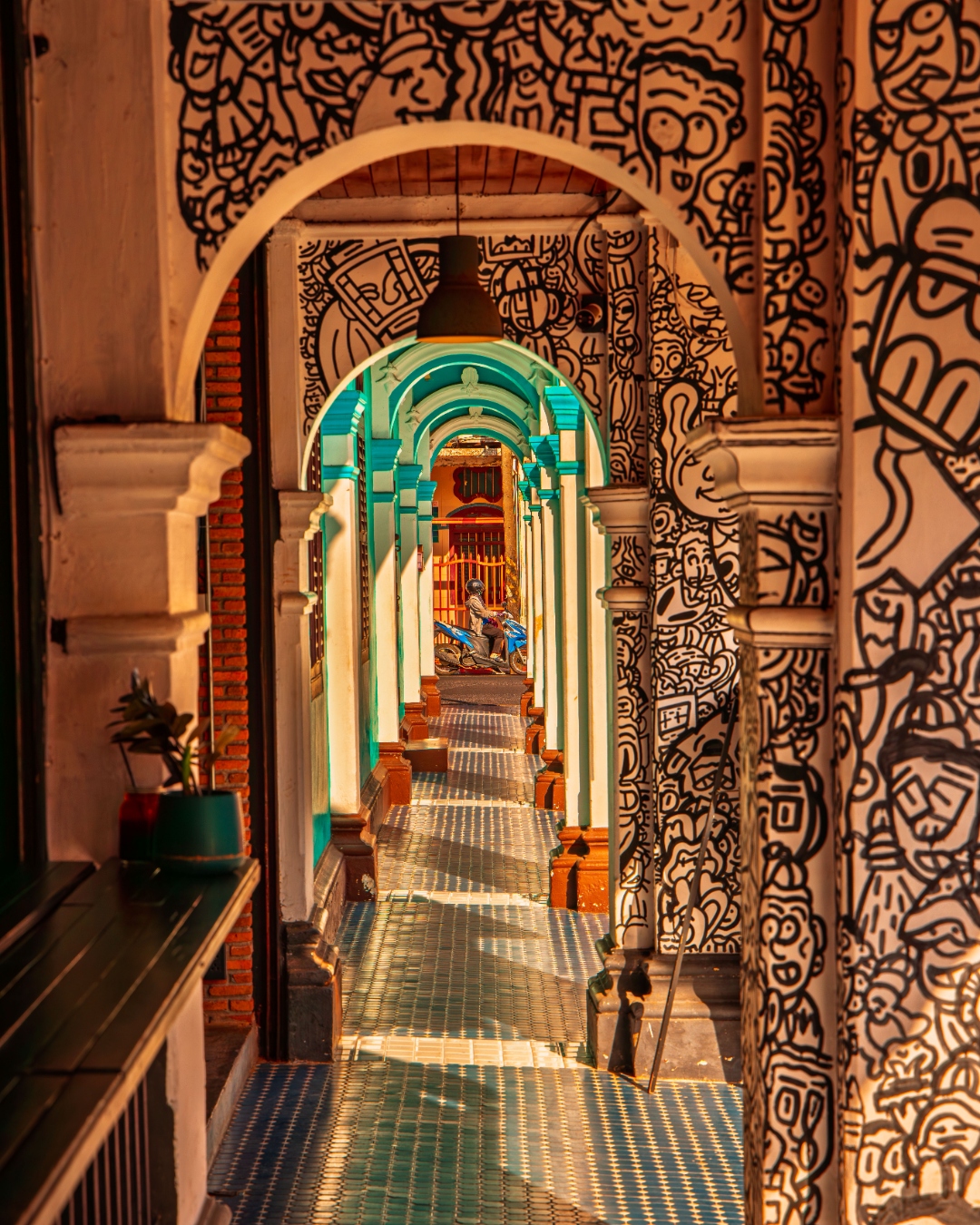 Arched colonnade with street art murals and dappled sunlight, Phuket Old Town — architectural photography