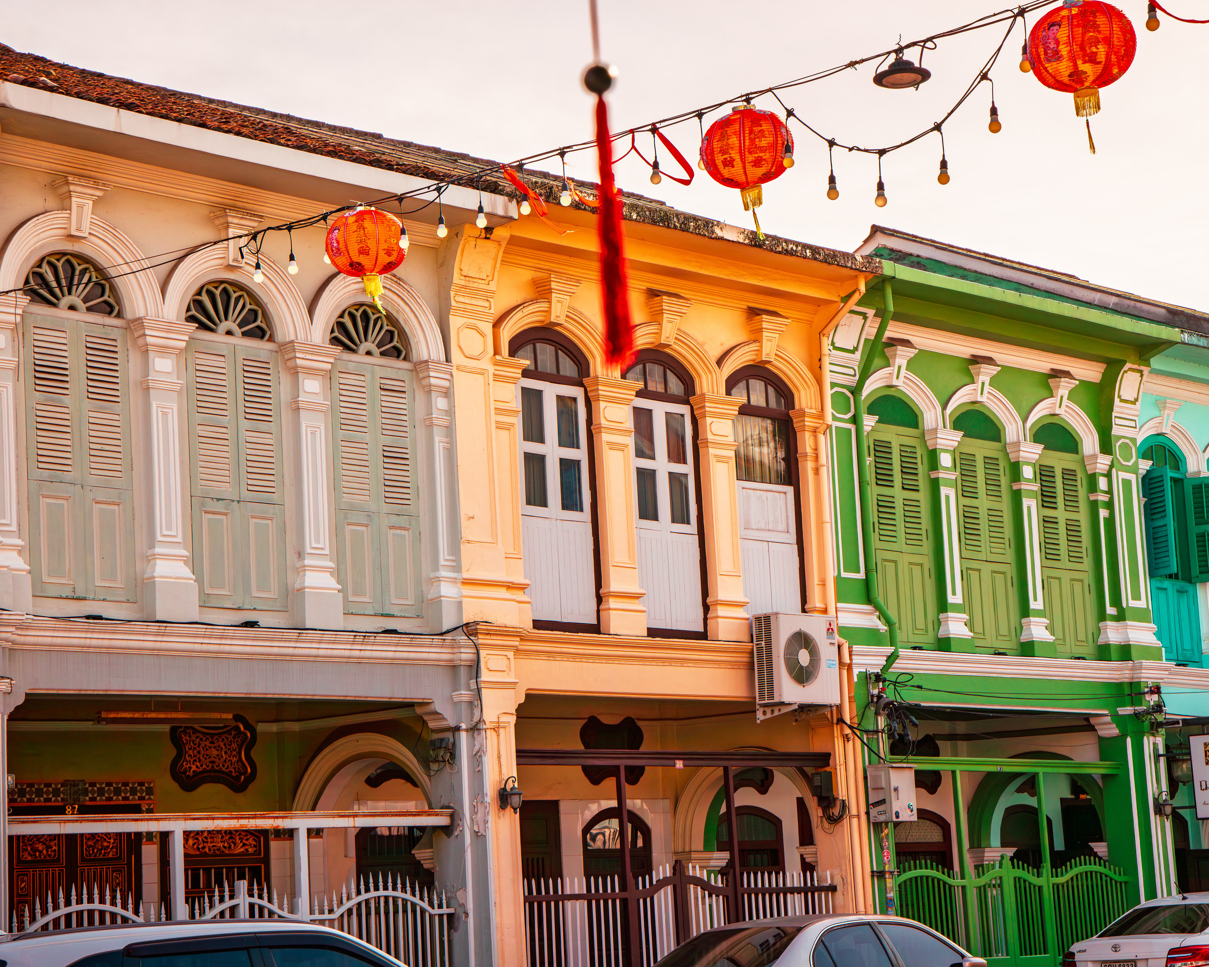 Ornate Sino-Portuguese shophouse facades with red lanterns, Phuket Old Town — architectural photography