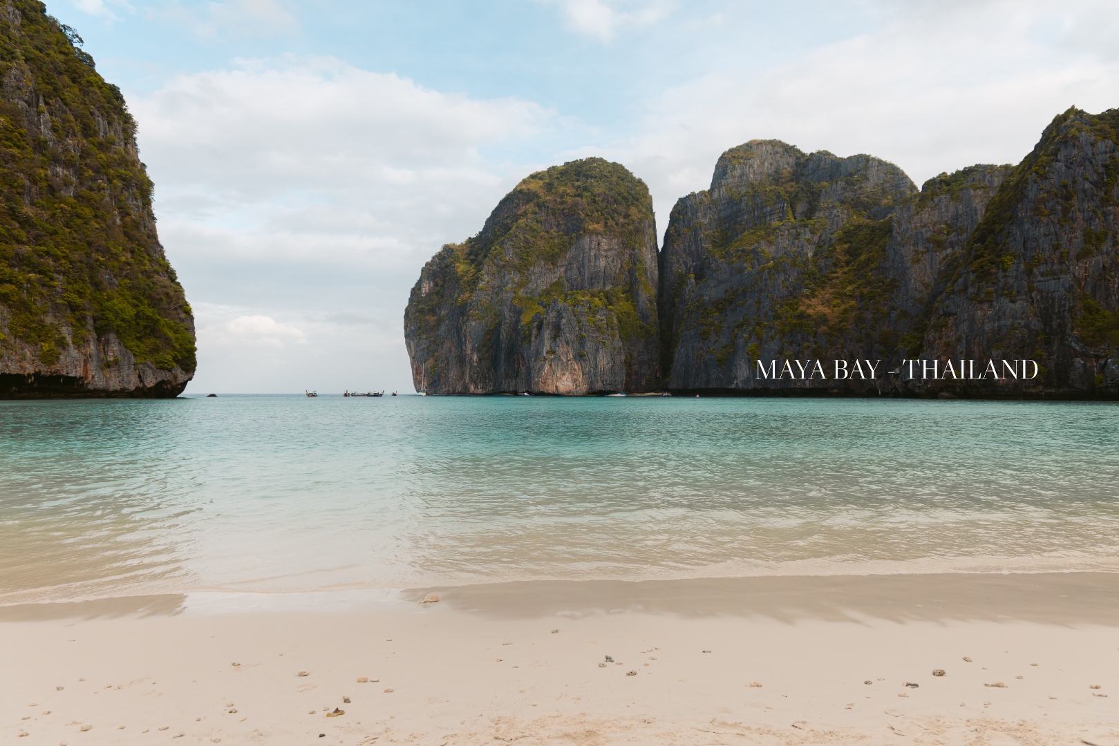 Maya Bay from the sand, turquoise water enclosed by towering limestone cliffs, Phi Phi Islands, Thailand — landscape photography