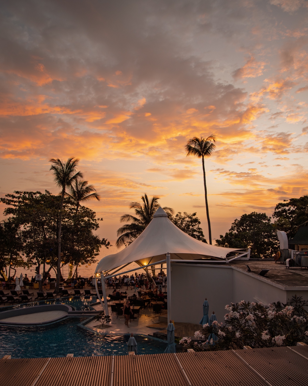Resort pool and tensile canopy silhouetted against a dramatic sunset — hospitality photography by Samuel John Ford