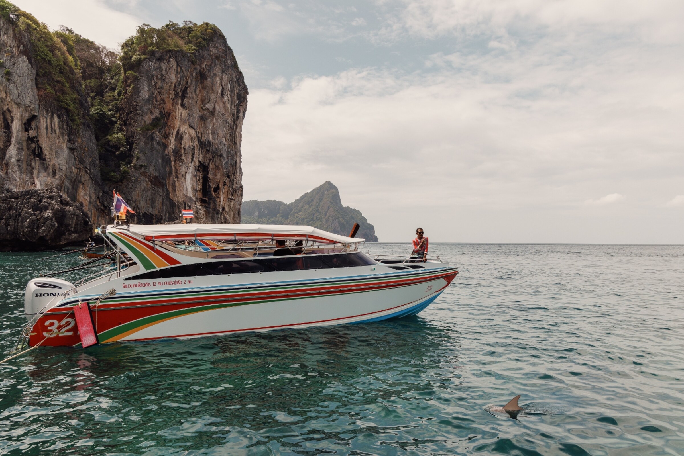 Colourful Thai speedboat with Honda outboard engine anchored near limestone cliffs, Phi Phi Islands — travel photography