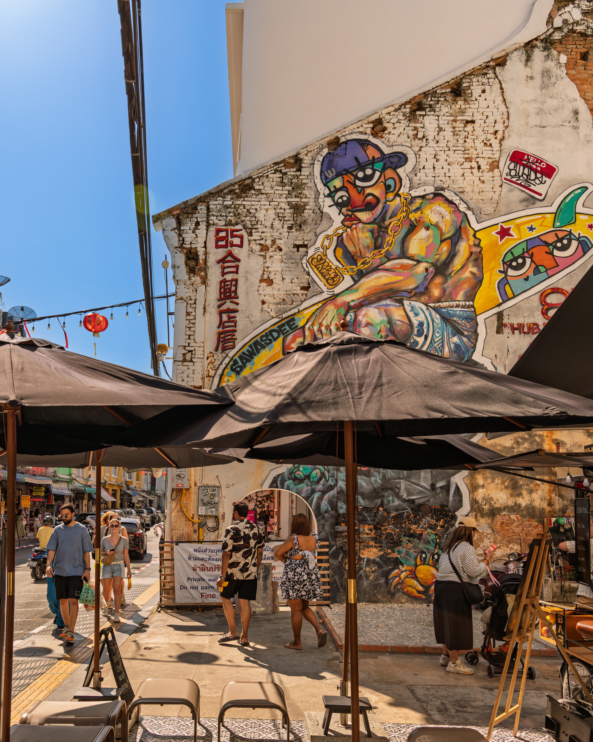 Vibrant street art mural with market umbrellas and pedestrians, Phuket — street photography